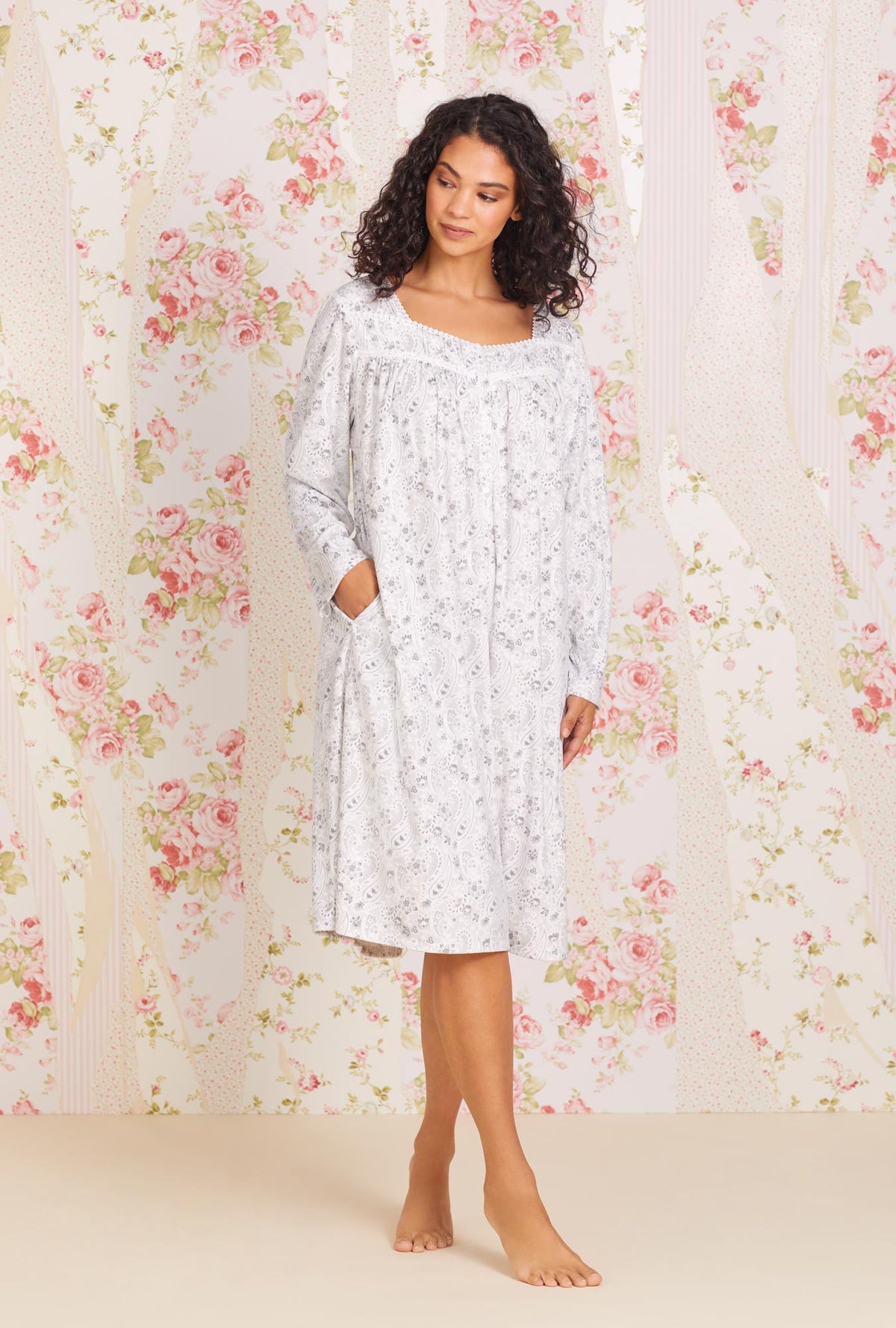 A lady wearing white long sleeve soft fleece waltz nightgown with grey paisley print.