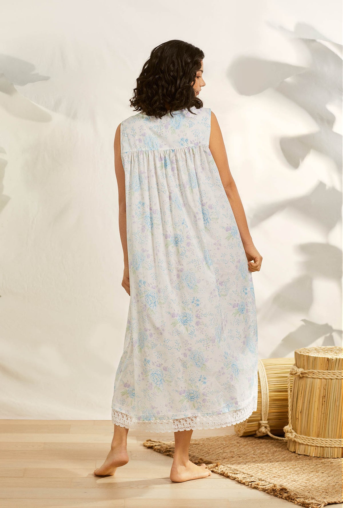 A lady wearing white sleeveless eileen cotton nightgown with summer garden print.