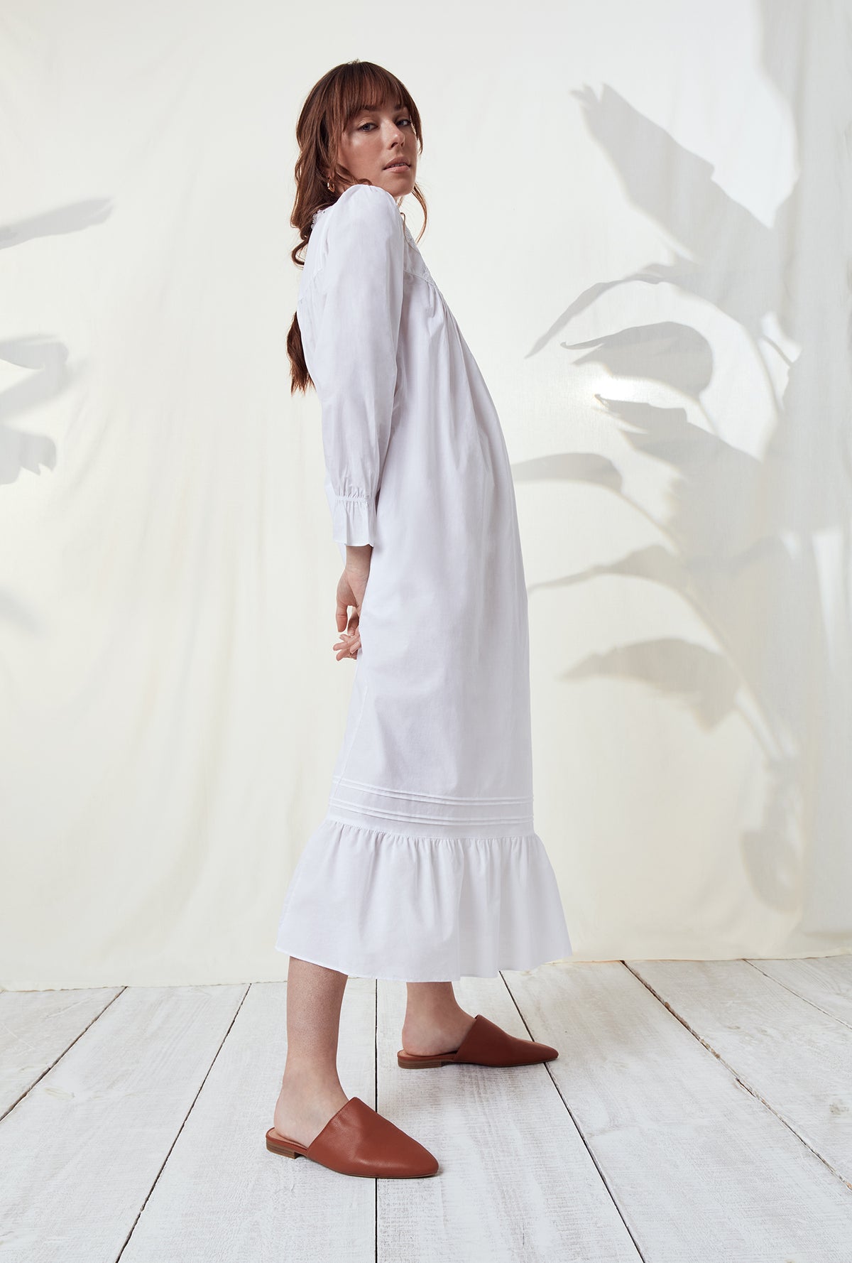 A lady wearing a white long sleeve nightgown.