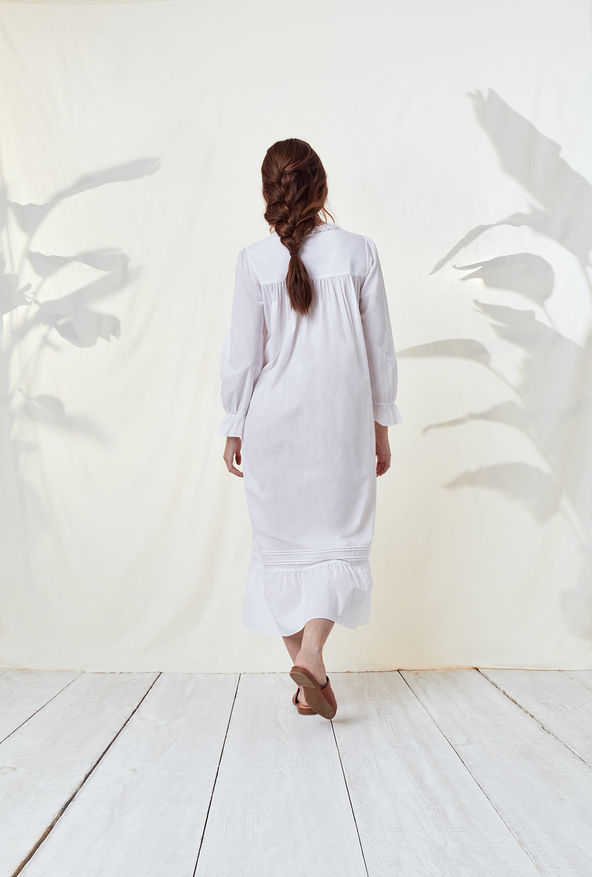 A lady wearing a white long sleeve nightgown.