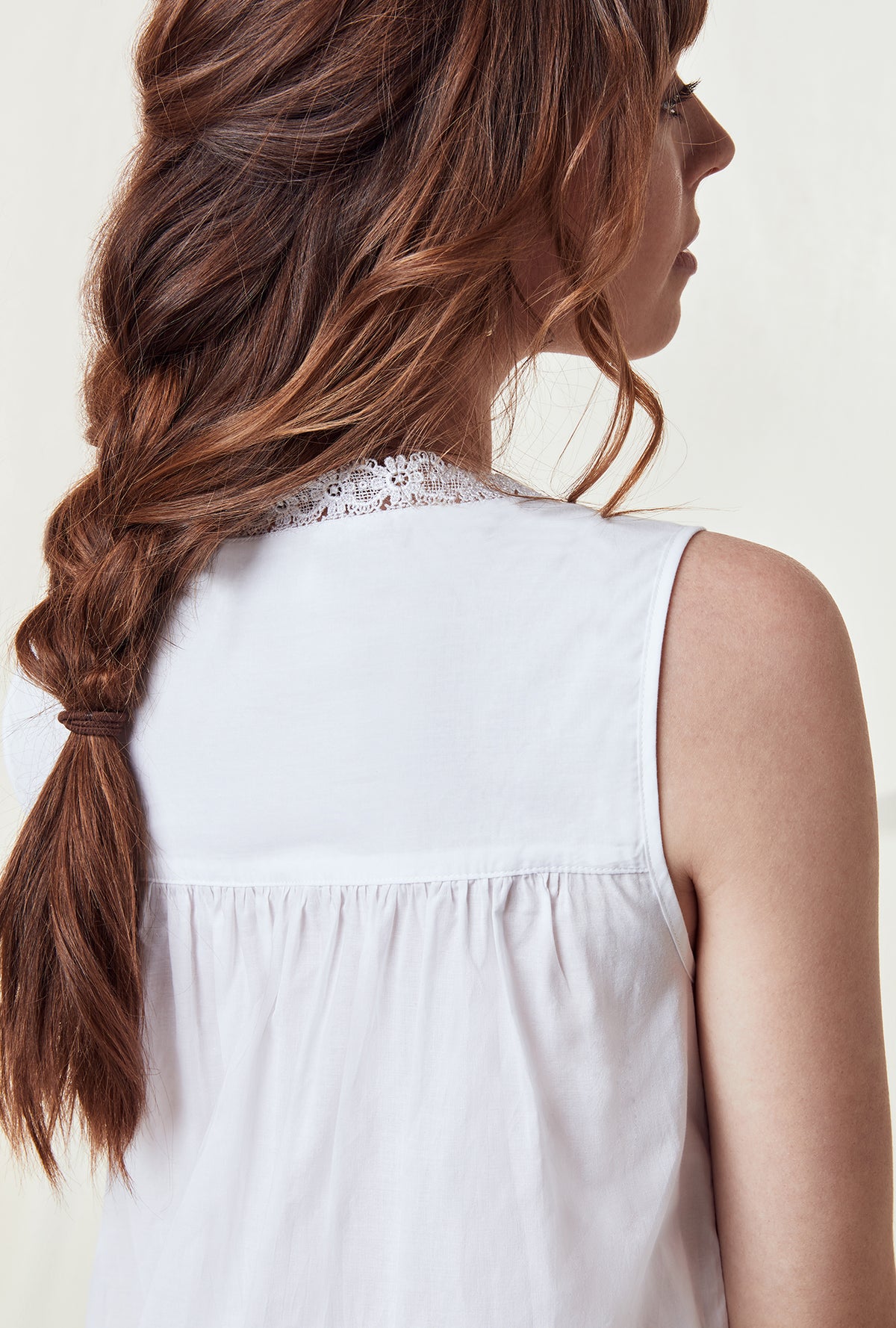 A lady wearing a white sleeveless nightgown.