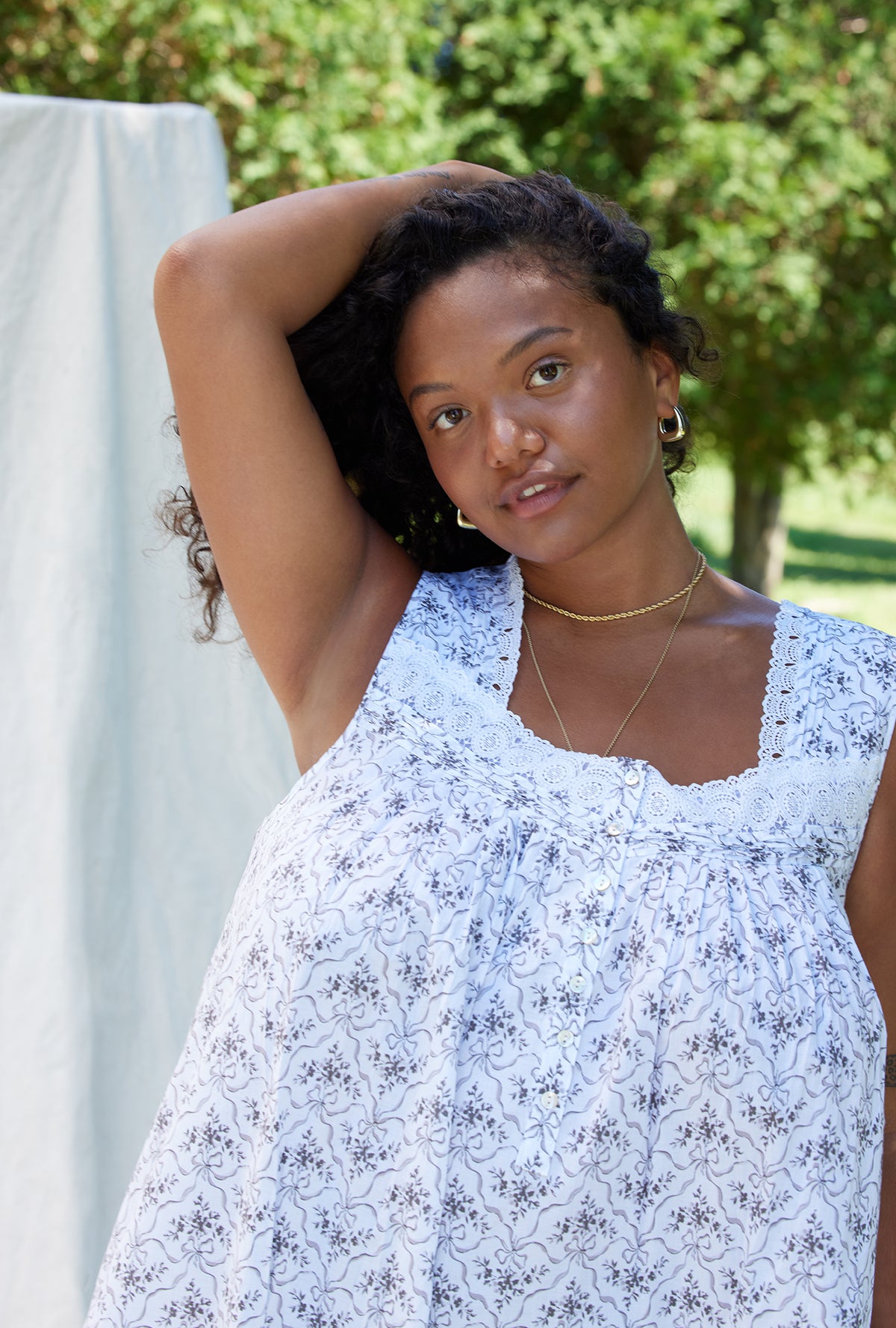 A lady wearing a white sleeveless grey ribbon floral cotton nightgown.