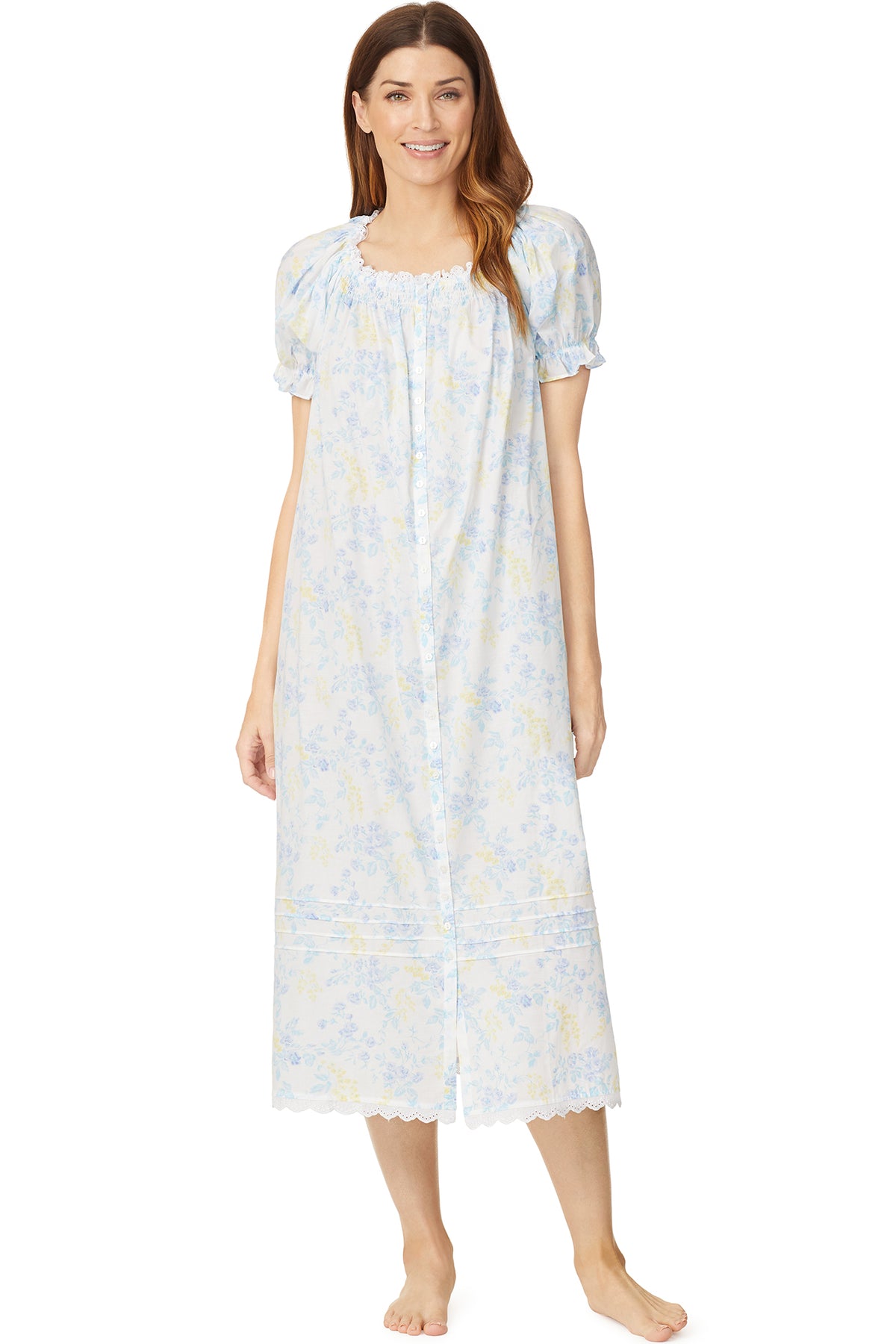 A lady wearing a white cap sleeve long nightdress with a multi colour floral pattern.