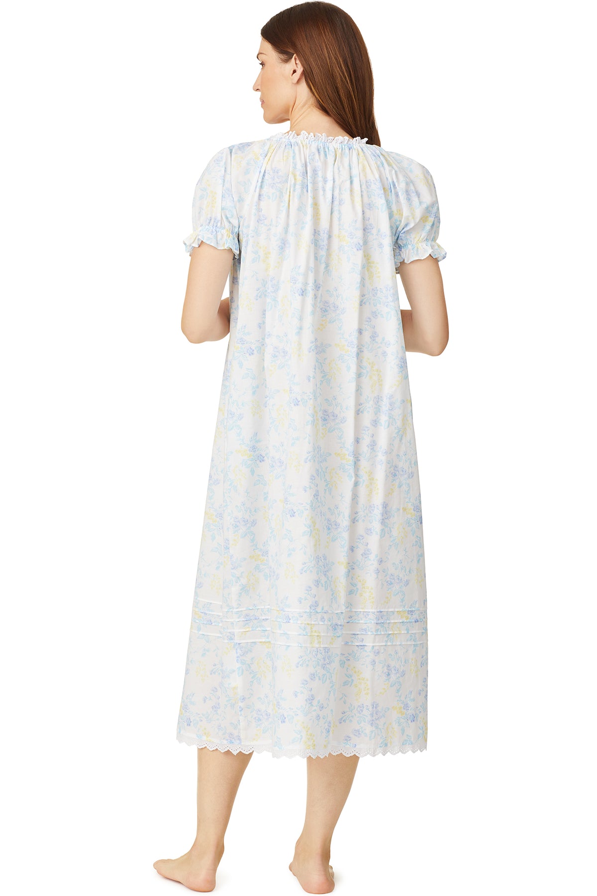 A lady wearing a white cap sleeve long nightdress with a multi colour floral pattern.
