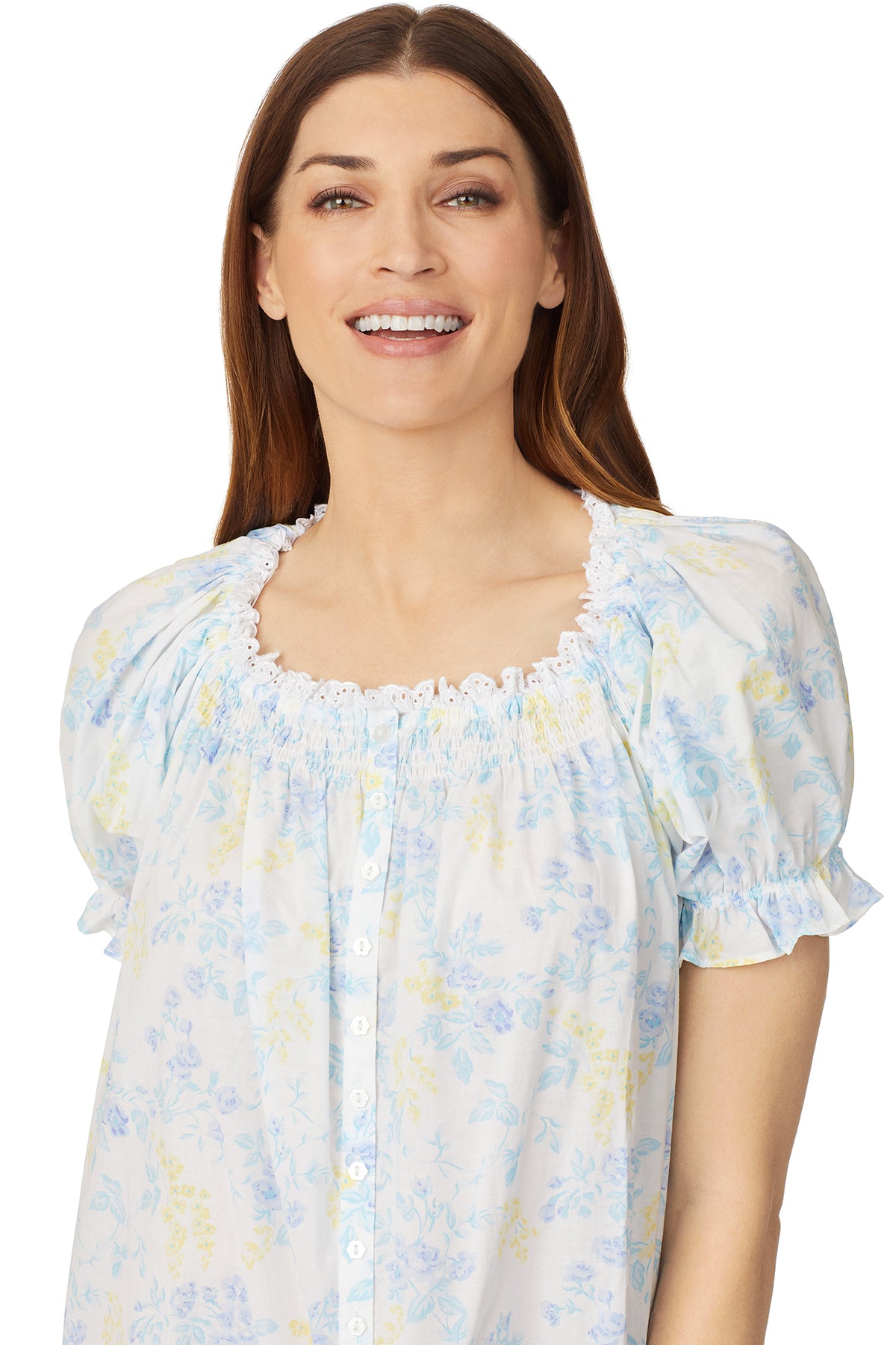 Upper part of a lady wearing a white cap sleeve long nightdress with a multi colour floral pattern.
