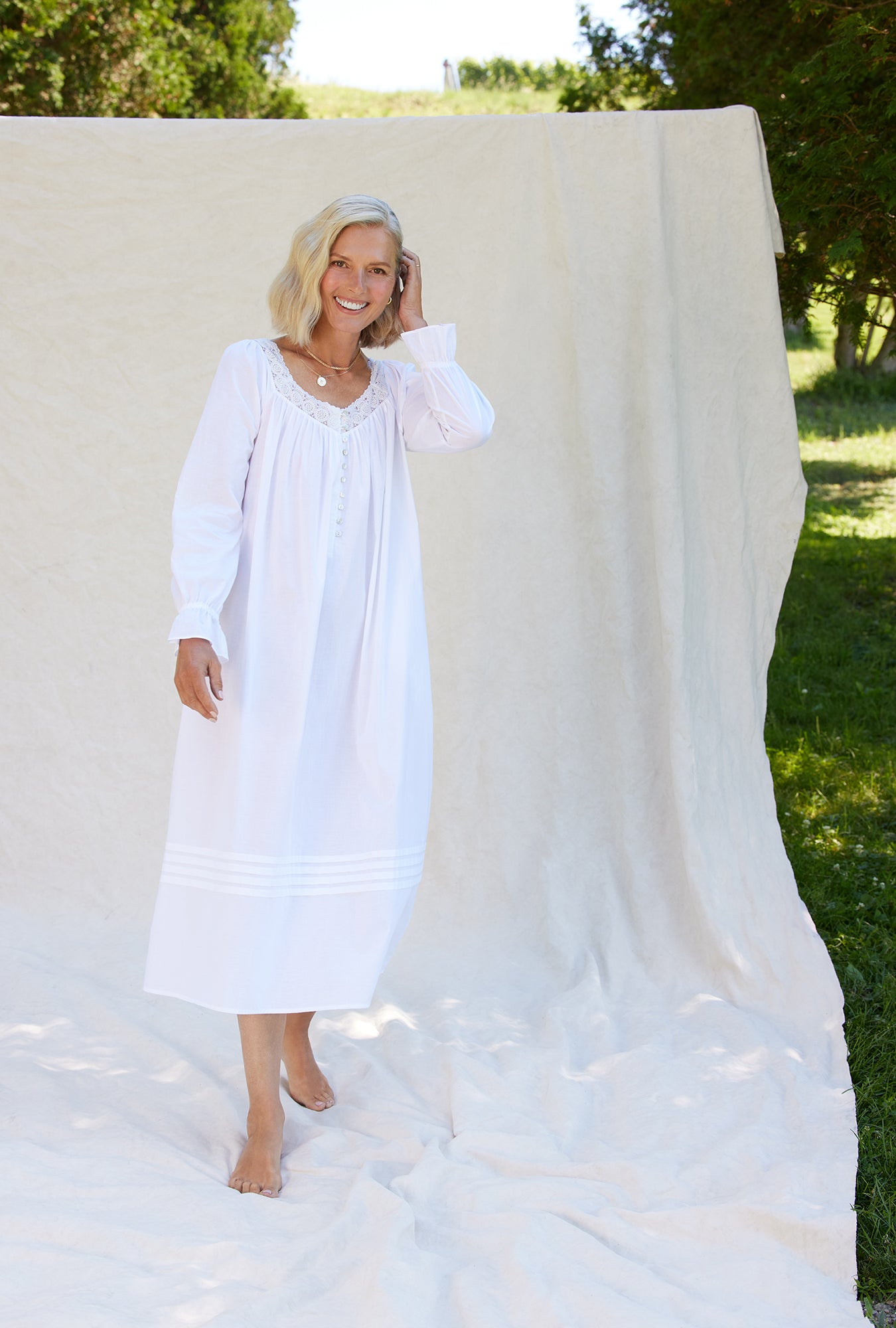A lady wearing a white long sleeve cotton nightgown.
