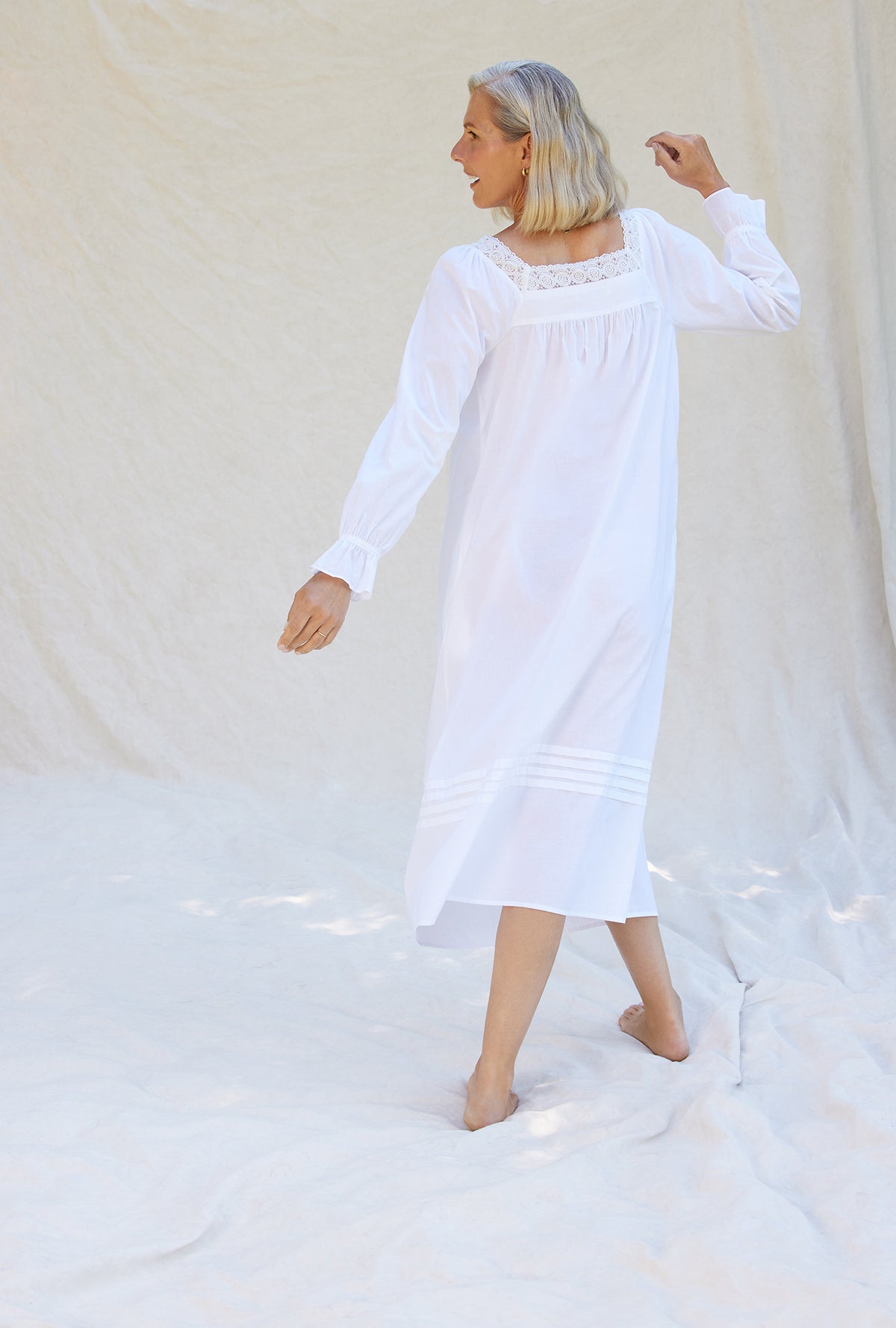 A lady wearing a white long sleeve cotton nightgown.