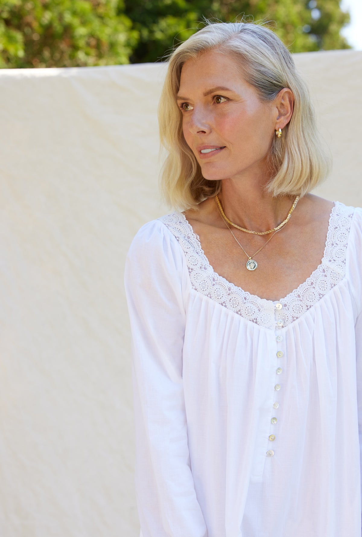 A lady wearing a white long sleeve cotton nightgown.