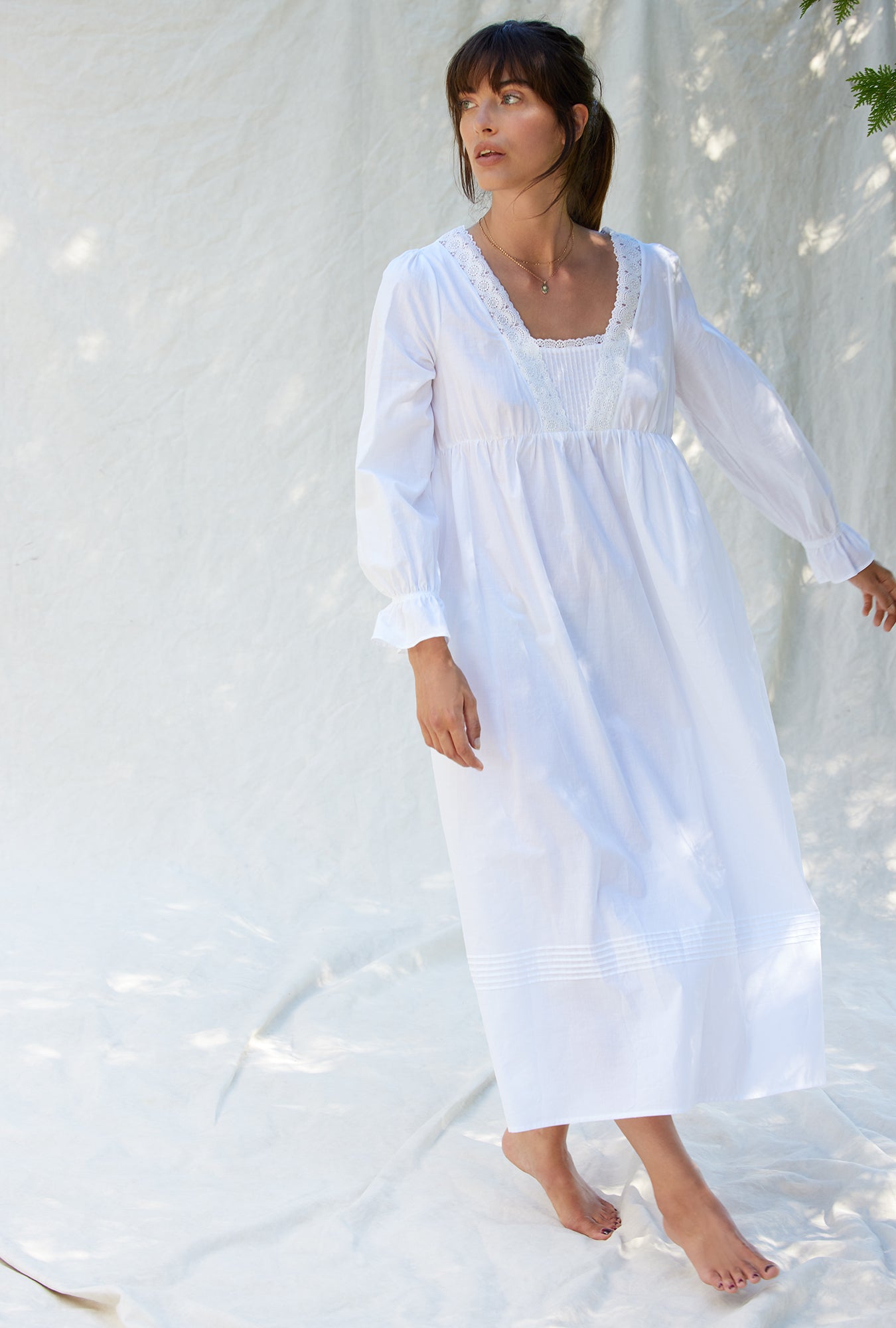 A lady wearing a white long sleeve cotton nightgown.