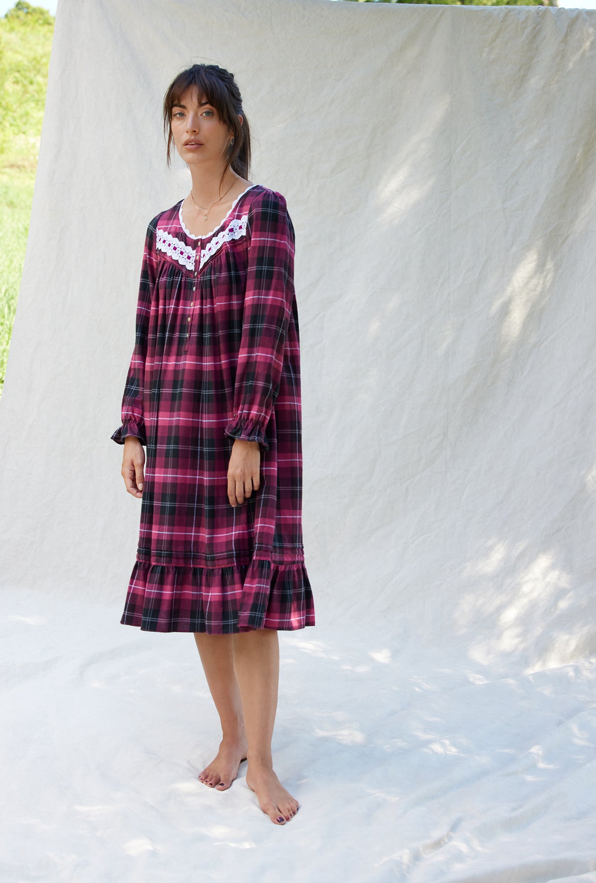 A lady wearing a holly berry plaid long sleeve flannel waltz nightgown.