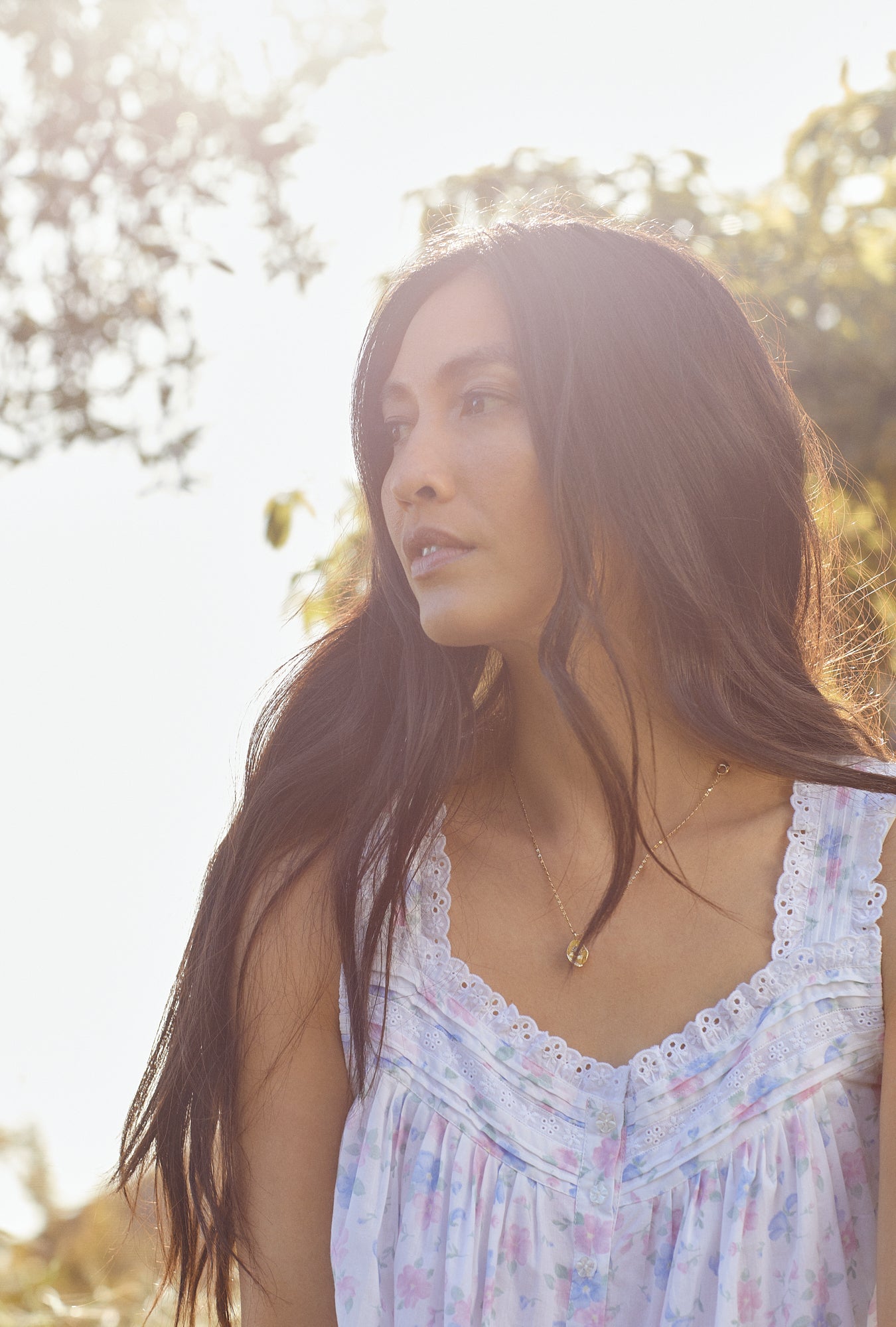 A lady wearing white sleeveless eileen nightgown with delicate floral print.