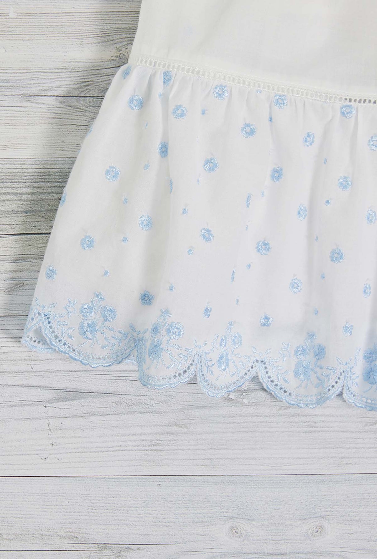 A lady wearing white sleeveless eileen scallop floral embroidery chemise.