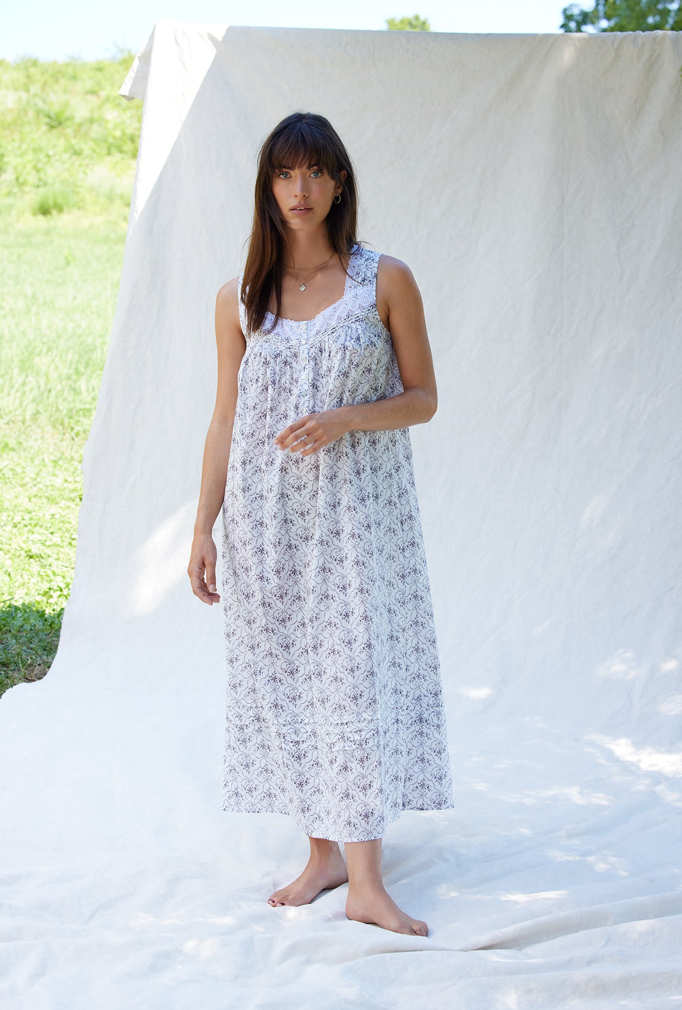 A lady wearing a white sleeveless grey ribbon floral cotton nightgown.