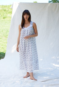 A lady wearing a white sleeveless grey ribbon floral cotton nightgown.