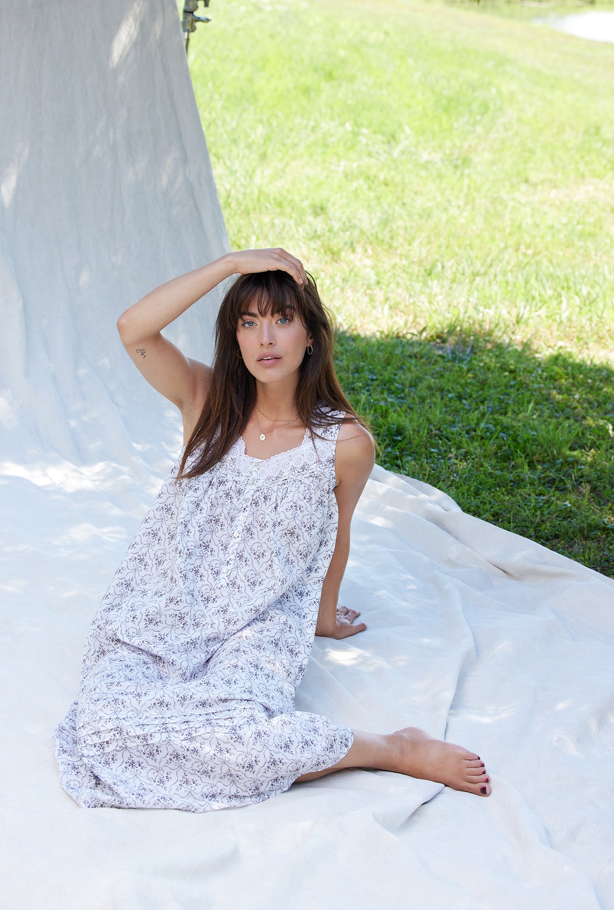 A lady wearing a white sleeveless grey ribbon floral cotton nightgown.