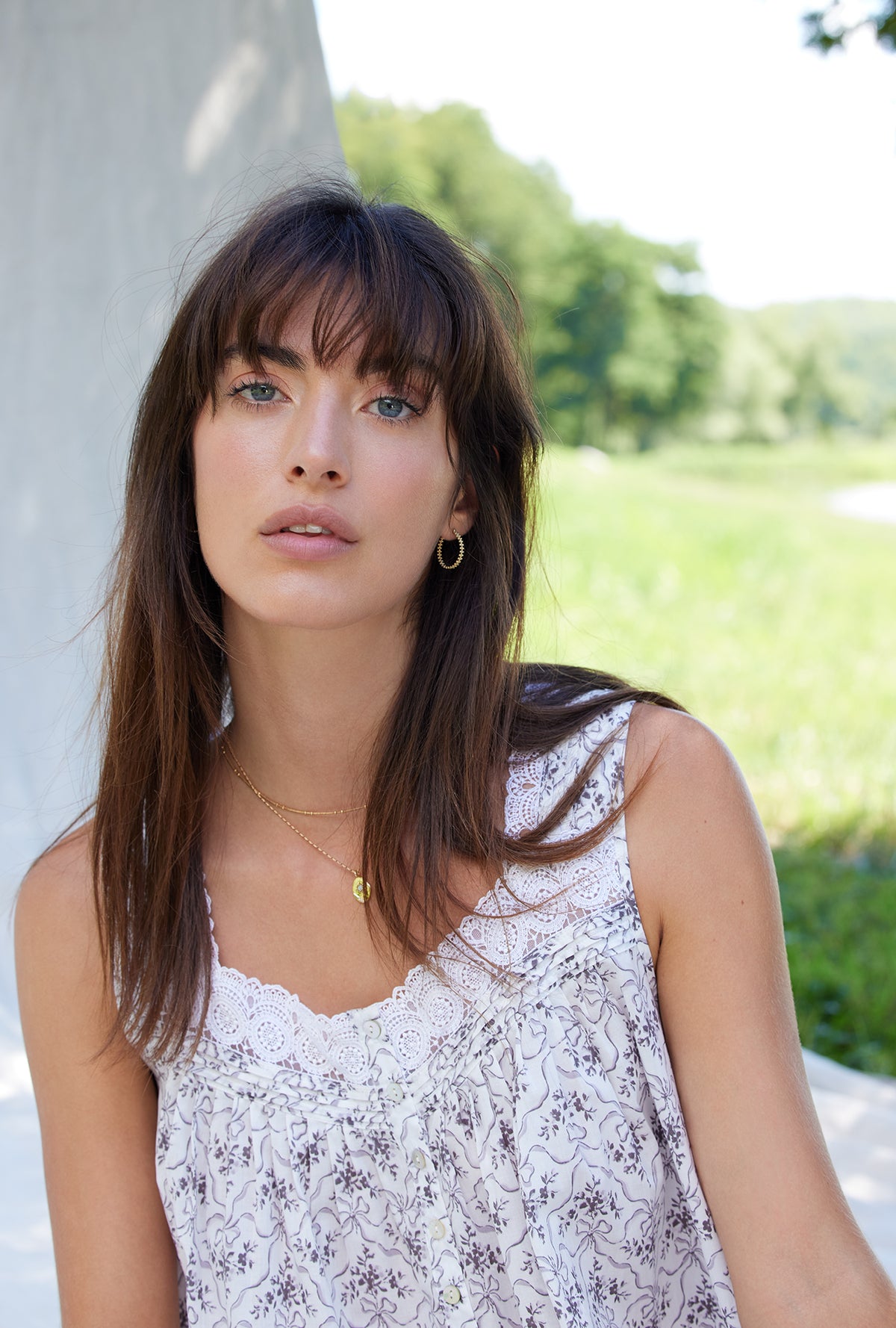 A lady wearing a white sleeveless grey ribbon floral cotton nightgown.