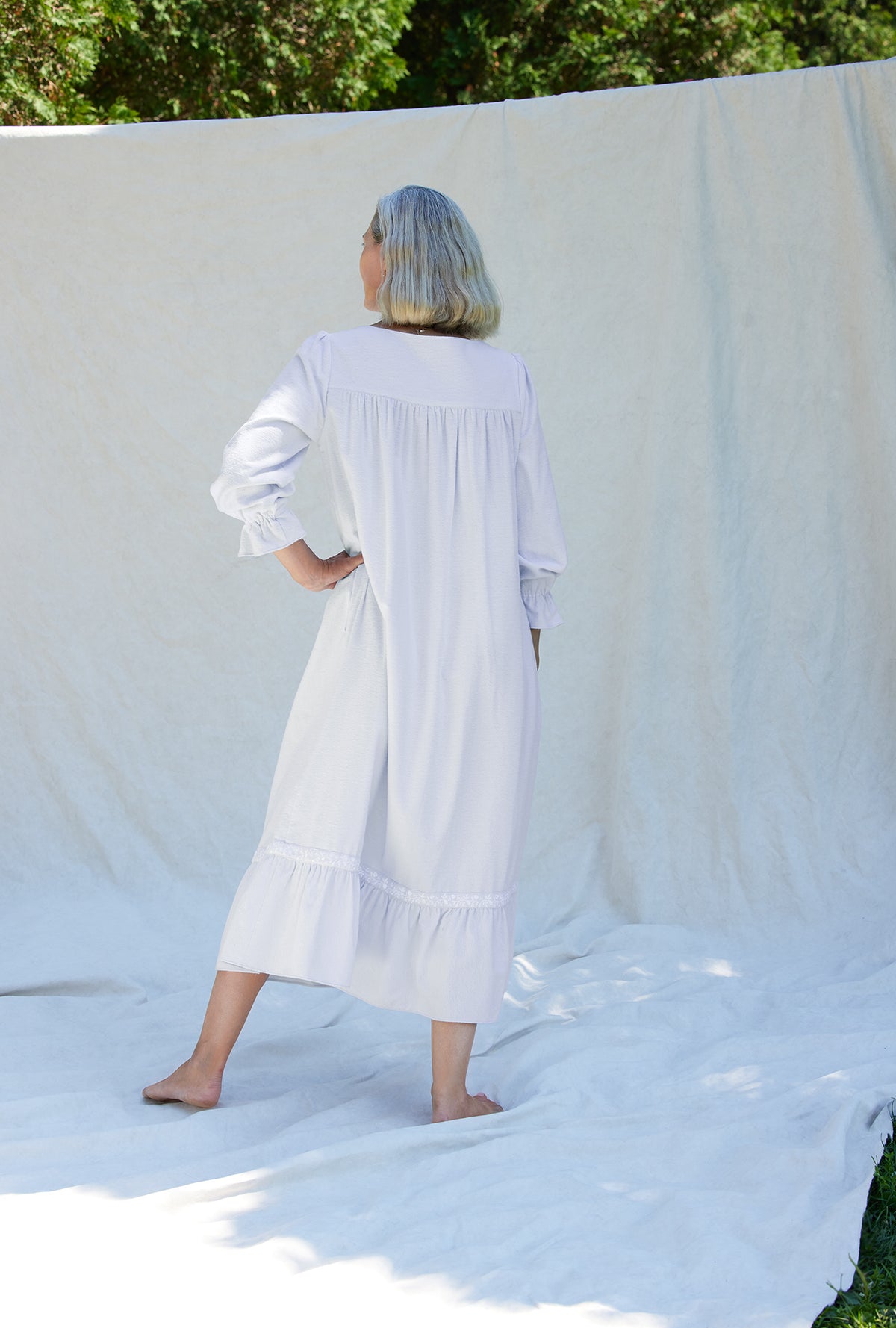 A lady wearing a white long sleeve cotton flannel embroidery nightgown.