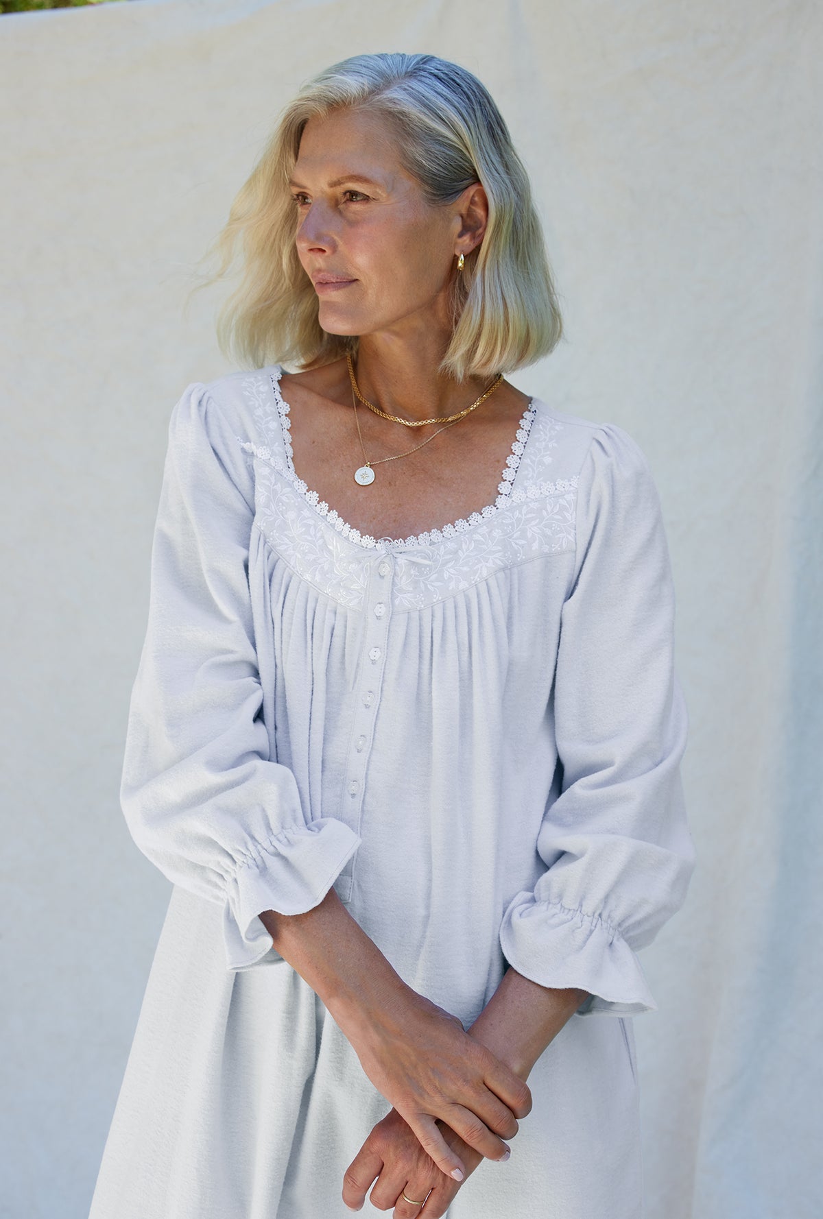 A lady wearing a white long sleeve cotton flannel embroidery nightgown.