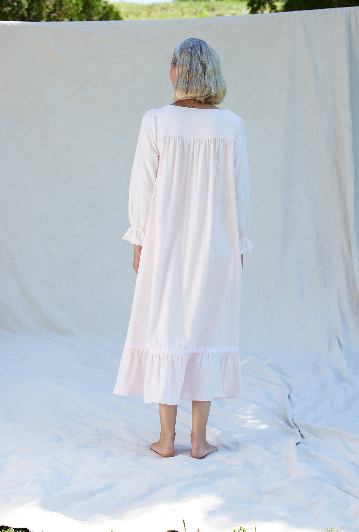 A lady wearing a white long sleeve cotton flannel embroidery nightgown.