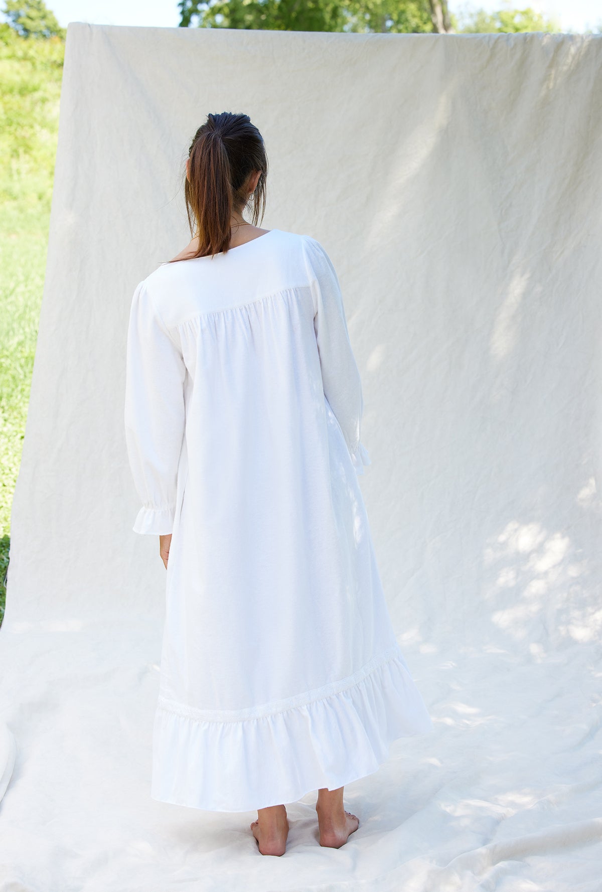 A lady wearing a white long sleeve cotton flannel embroidery nightgown.