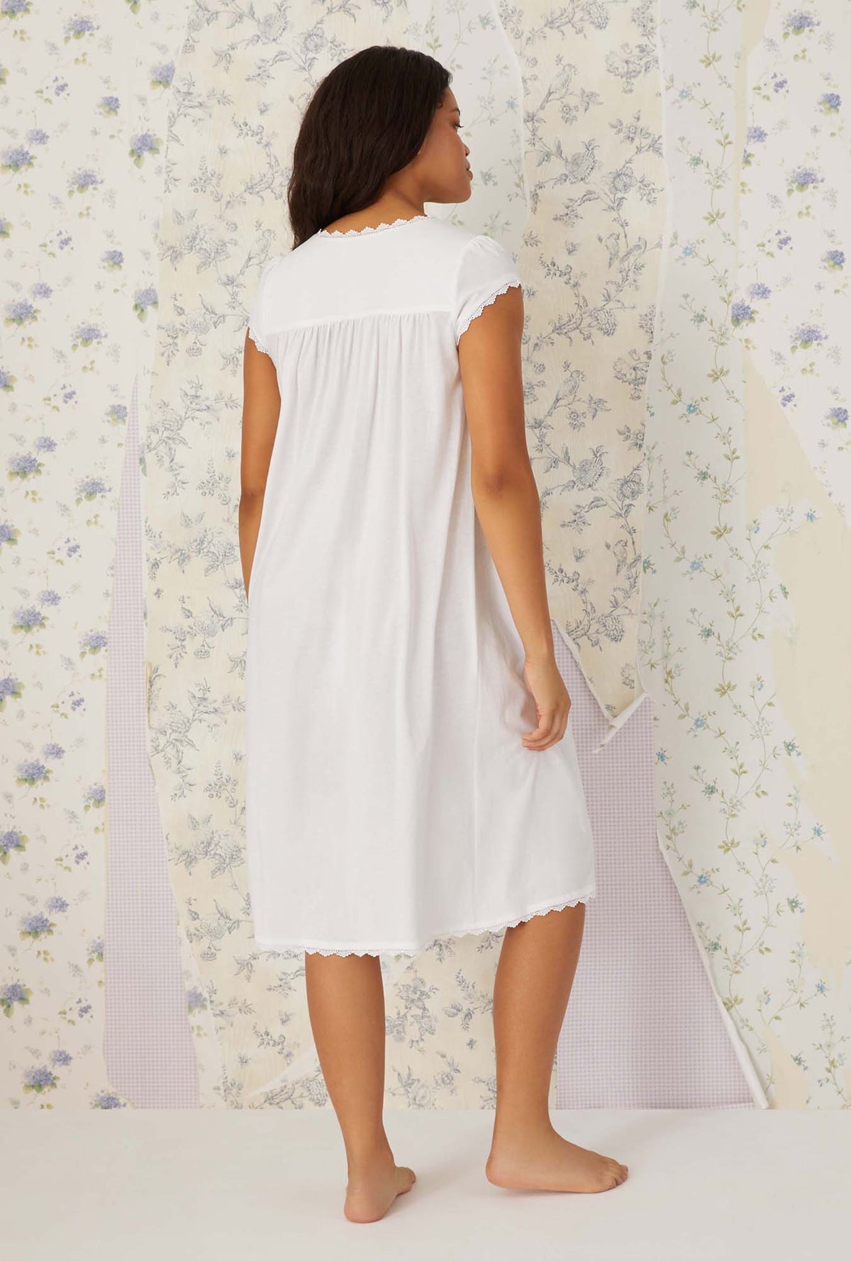 A lady wearing plus size white villa blanca waltz knit nightgown in a back view pose