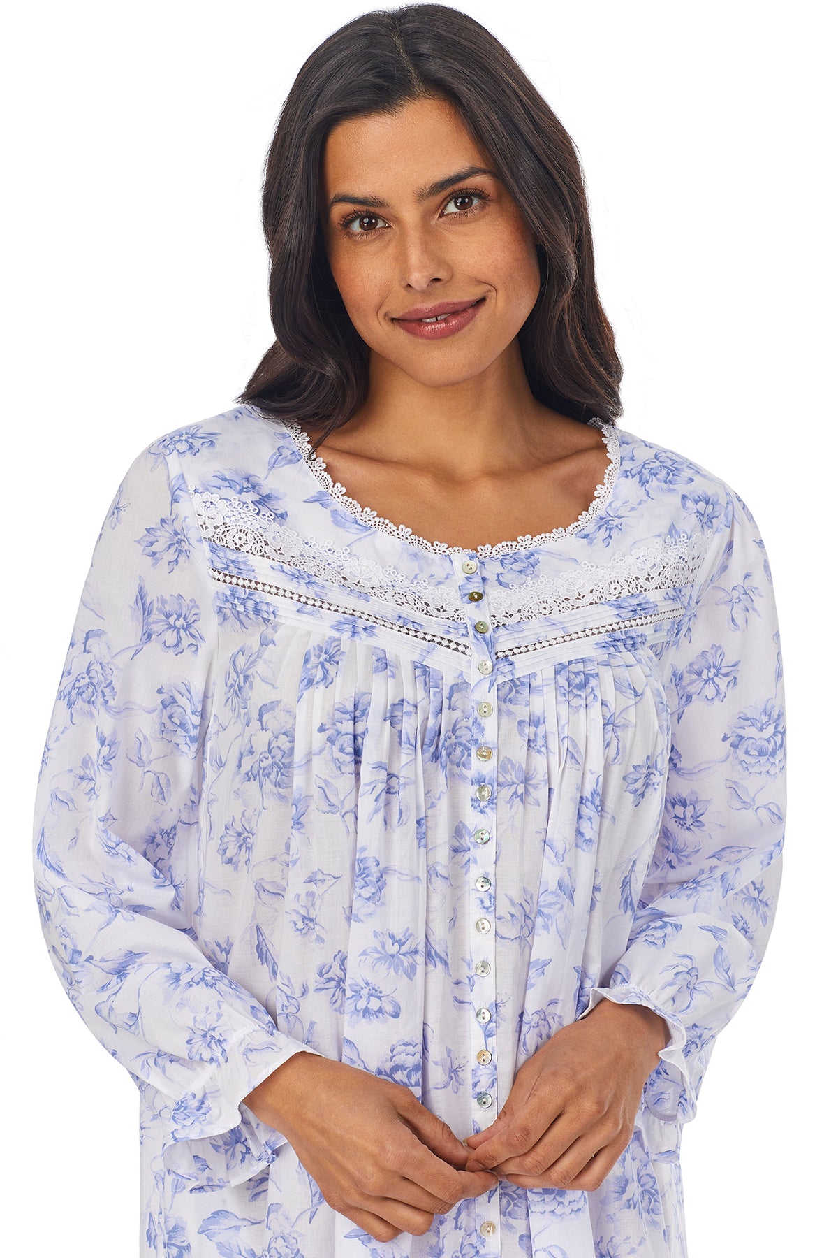 Upper part of a lady wearing a white long sleeve button front robe with blue floral pattern.