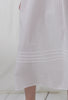 A lady wearing a white sleeveless dobby stripe gown.