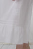 A lady wearing a white sleeveless nightgown.