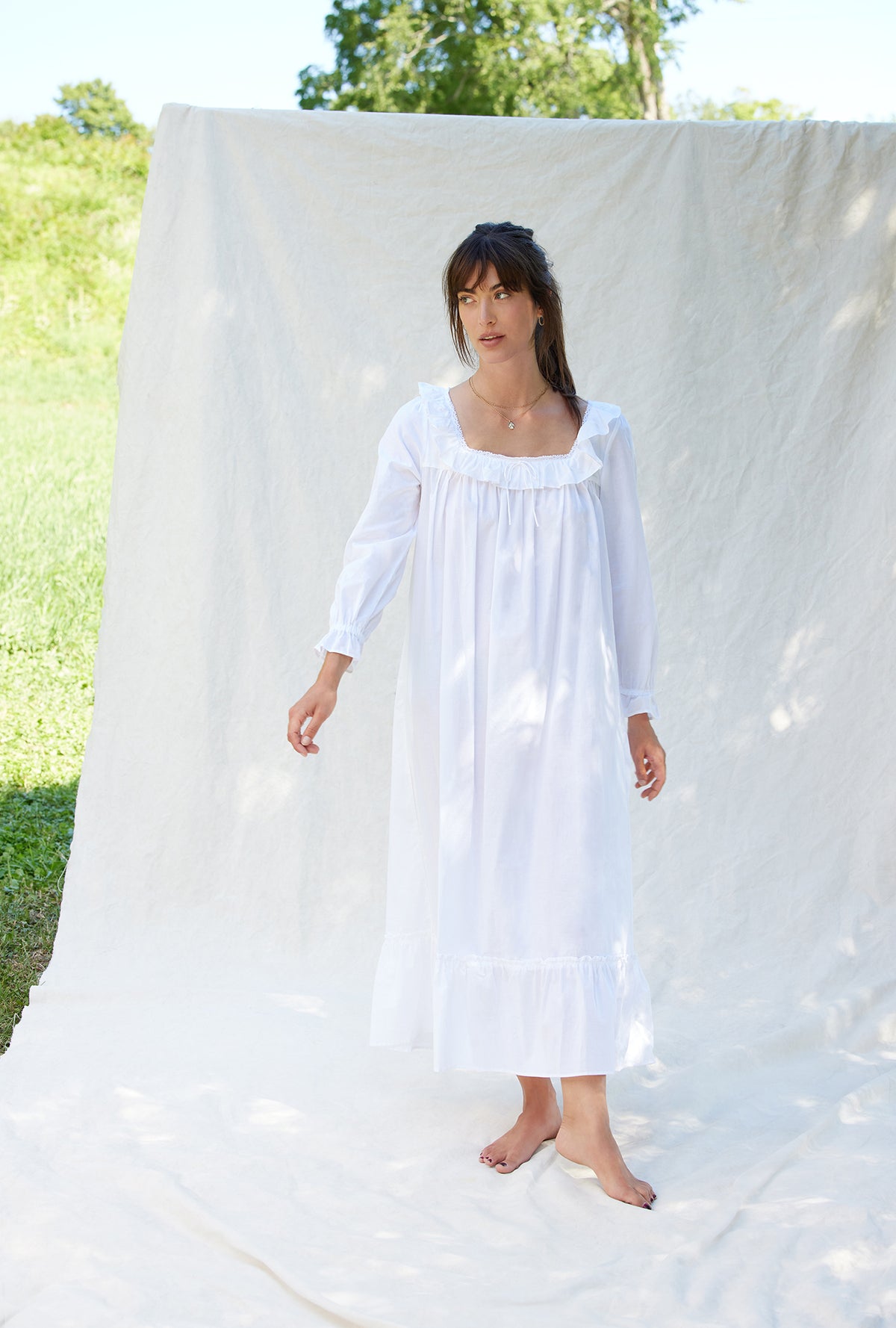 A lady wearing a white long sleeve cotton nightgown.