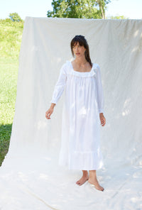 A lady wearing a white long sleeve cotton nightgown.