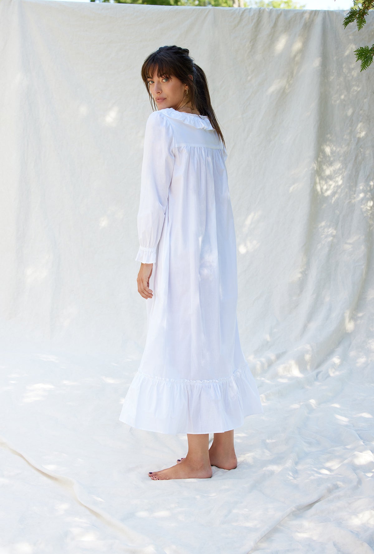 A lady wearing a white long sleeve cotton nightgown.