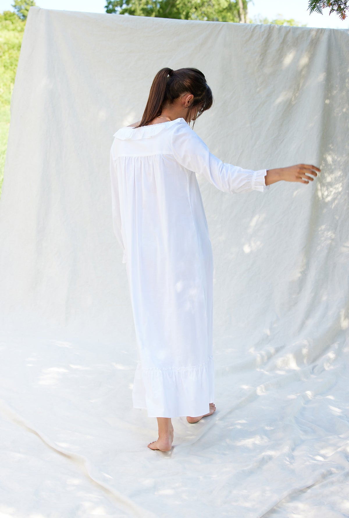 A lady wearing a white long sleeve cotton nightgown.