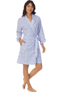 A lady wearing a white long sleeve shortie wrap with blue floral pattern.