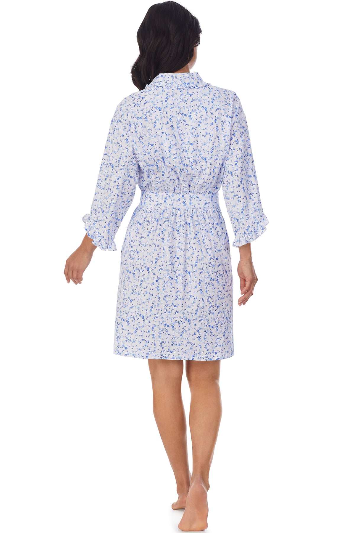 A lady wearing a white long sleeve shortie wrap with blue floral pattern.