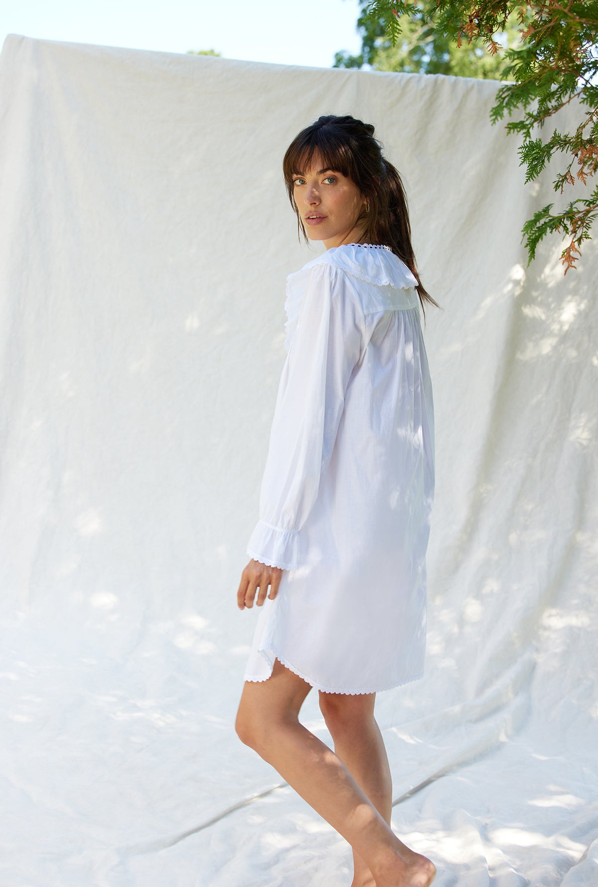 A lady wearing a white long sleeve clara poet nightshirt.