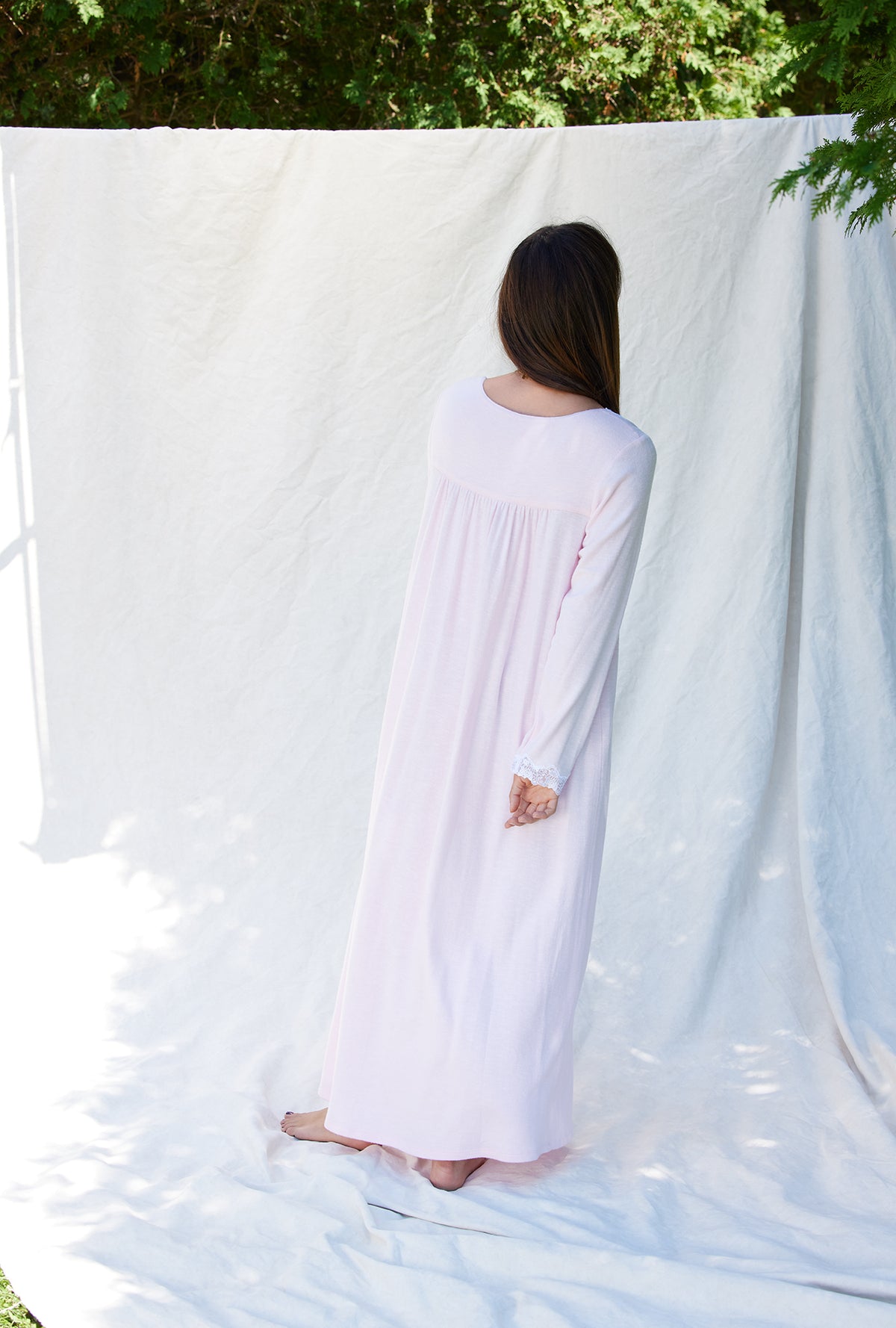 A lady wearing a rose long sleeve long nightgown.