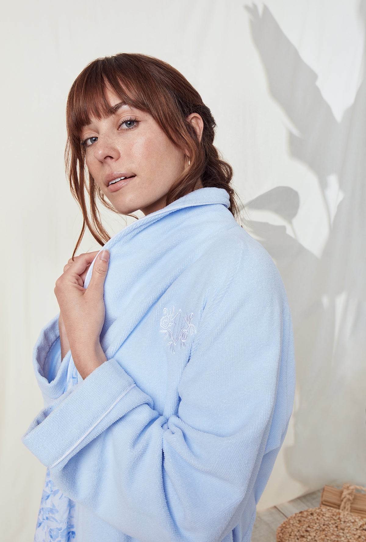 A lady wearing a terry blue long sleeve spa soft wrap robe.