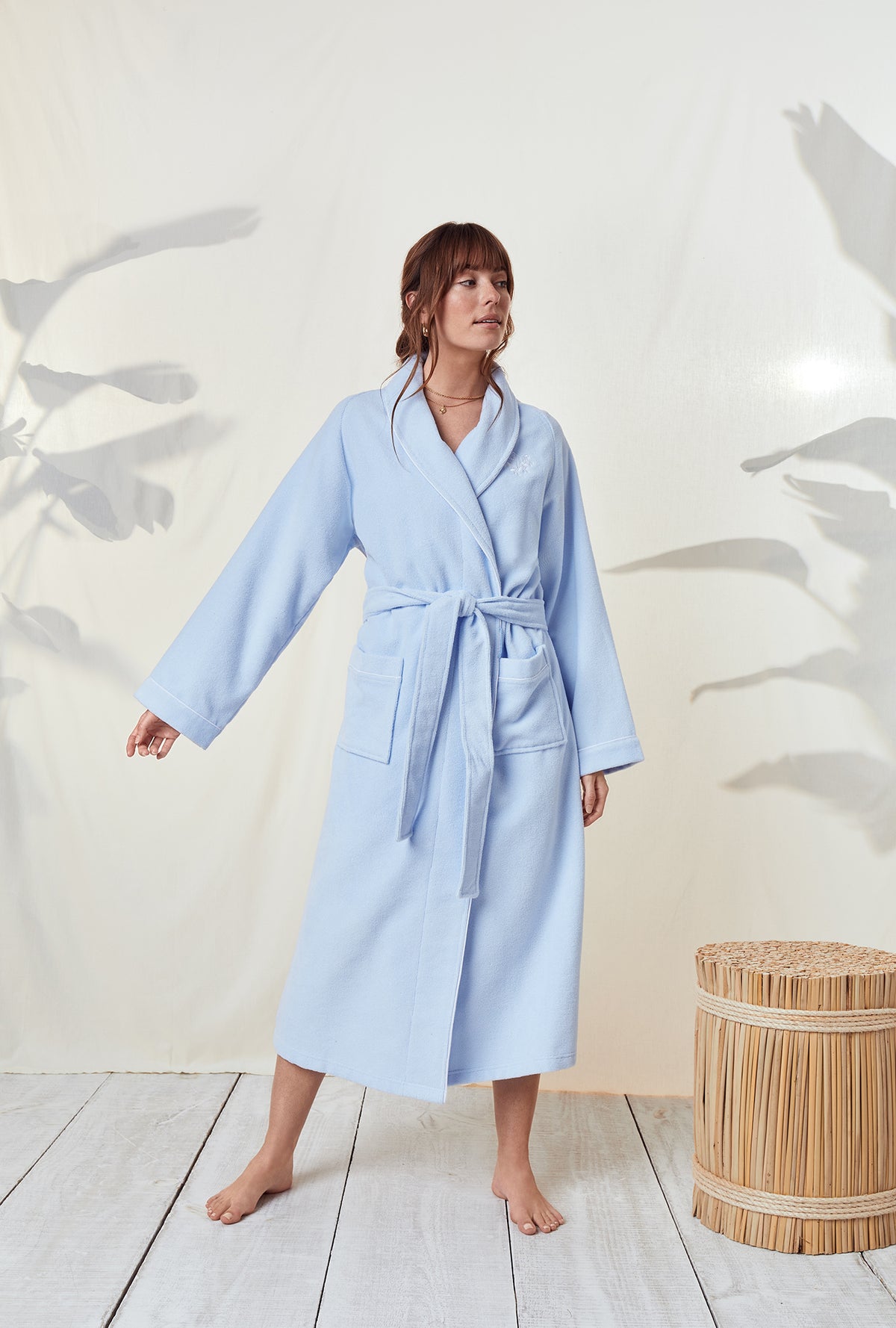 A lady wearing a terry blue long sleeve spa soft wrap robe.