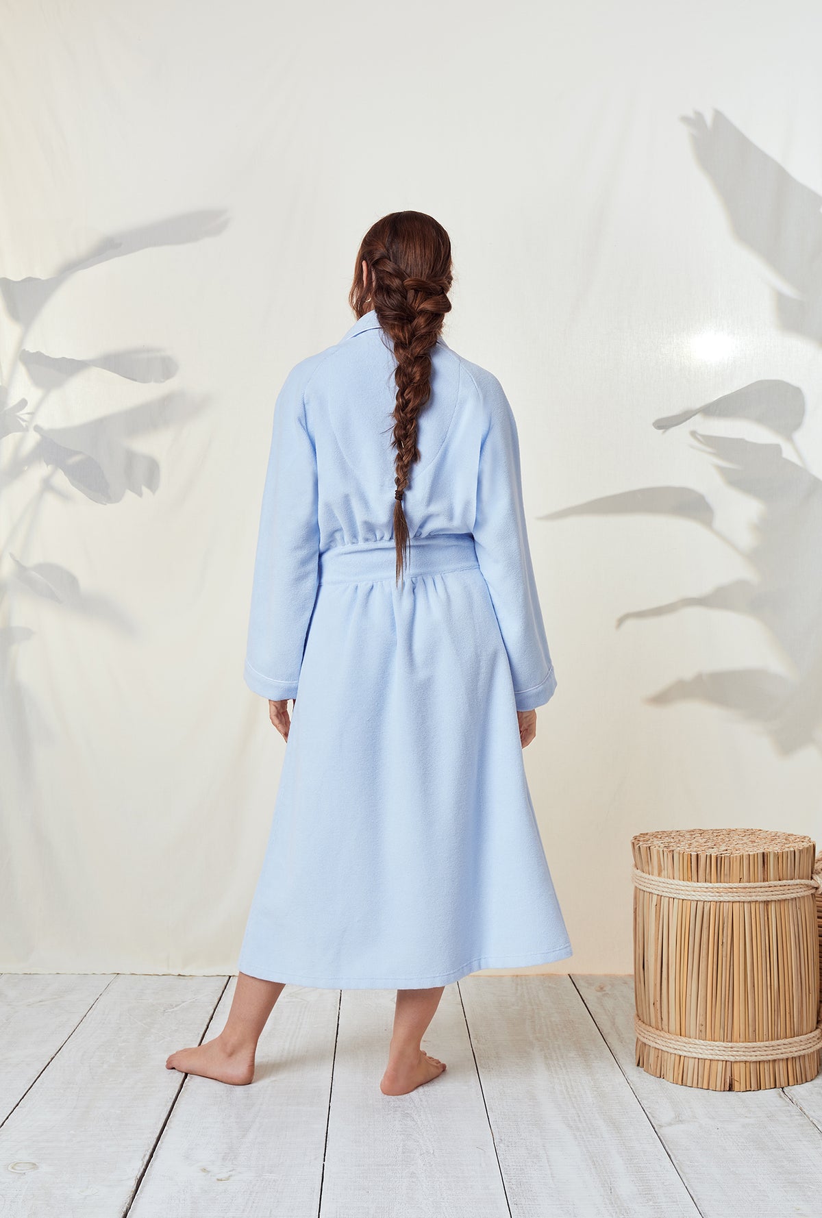 A lady wearing a terry blue long sleeve spa soft wrap robe.