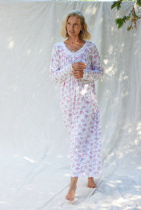 A lady wearing a pink and grey floral long sleeve long nightgown.