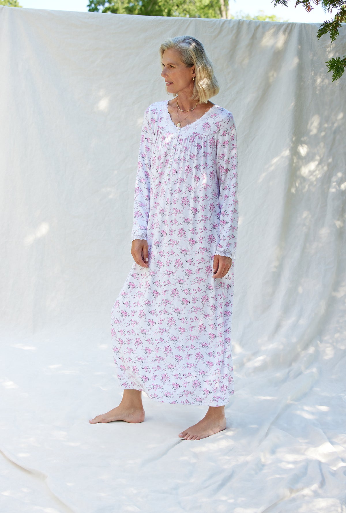 A lady wearing a pink and grey floral long sleeve long nightgown.