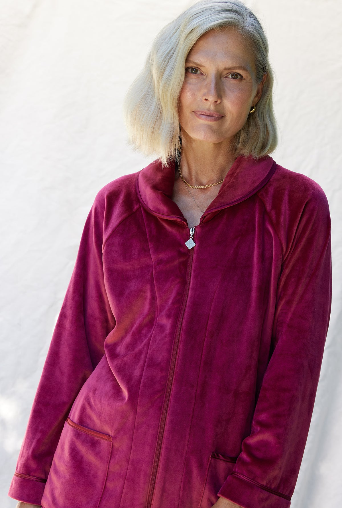 A lady wearing a crimson long sleeve velour short bed jacket.