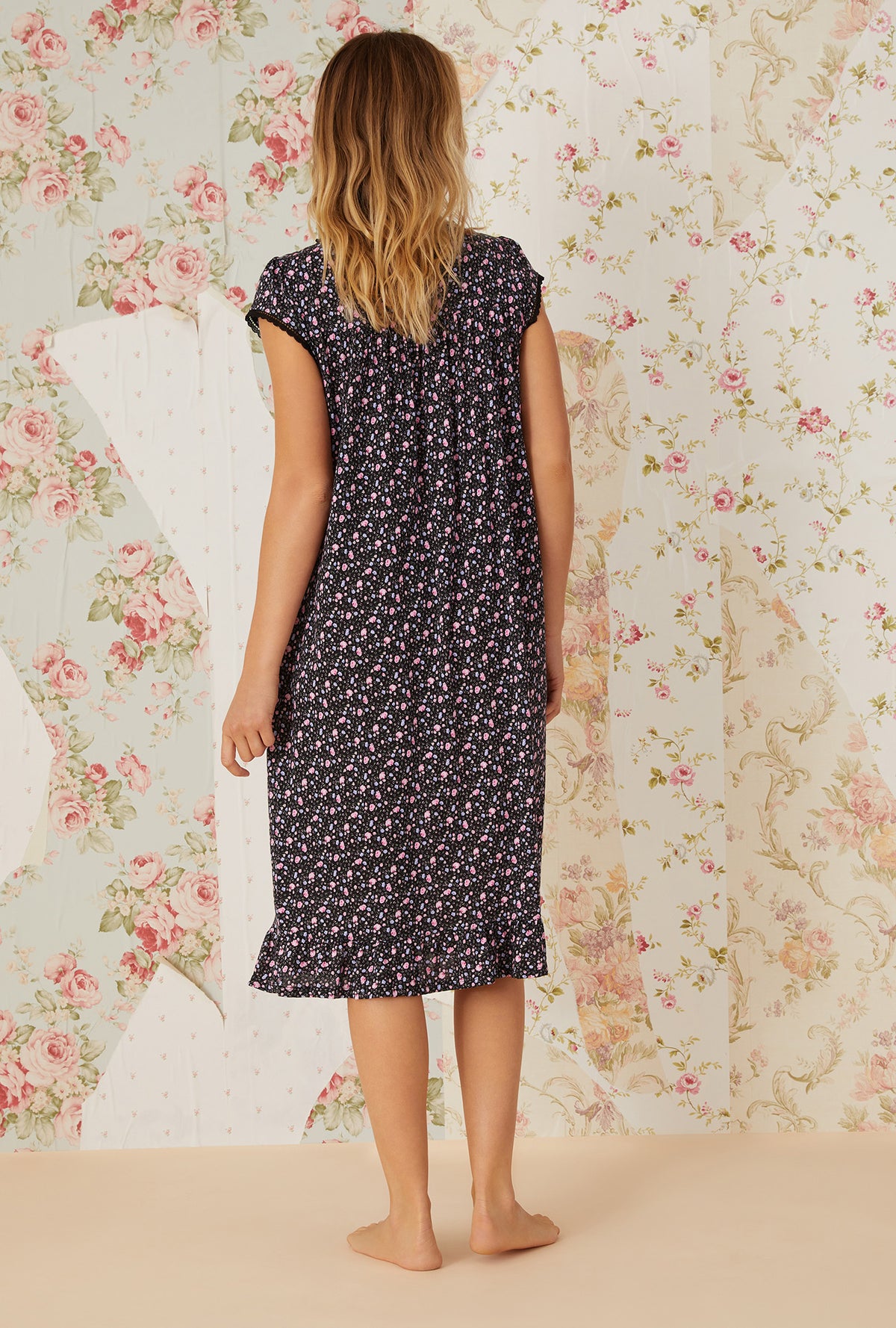 A lady wearing black cap sleeve cotton modal waltz knit nightgown with night blooms print.