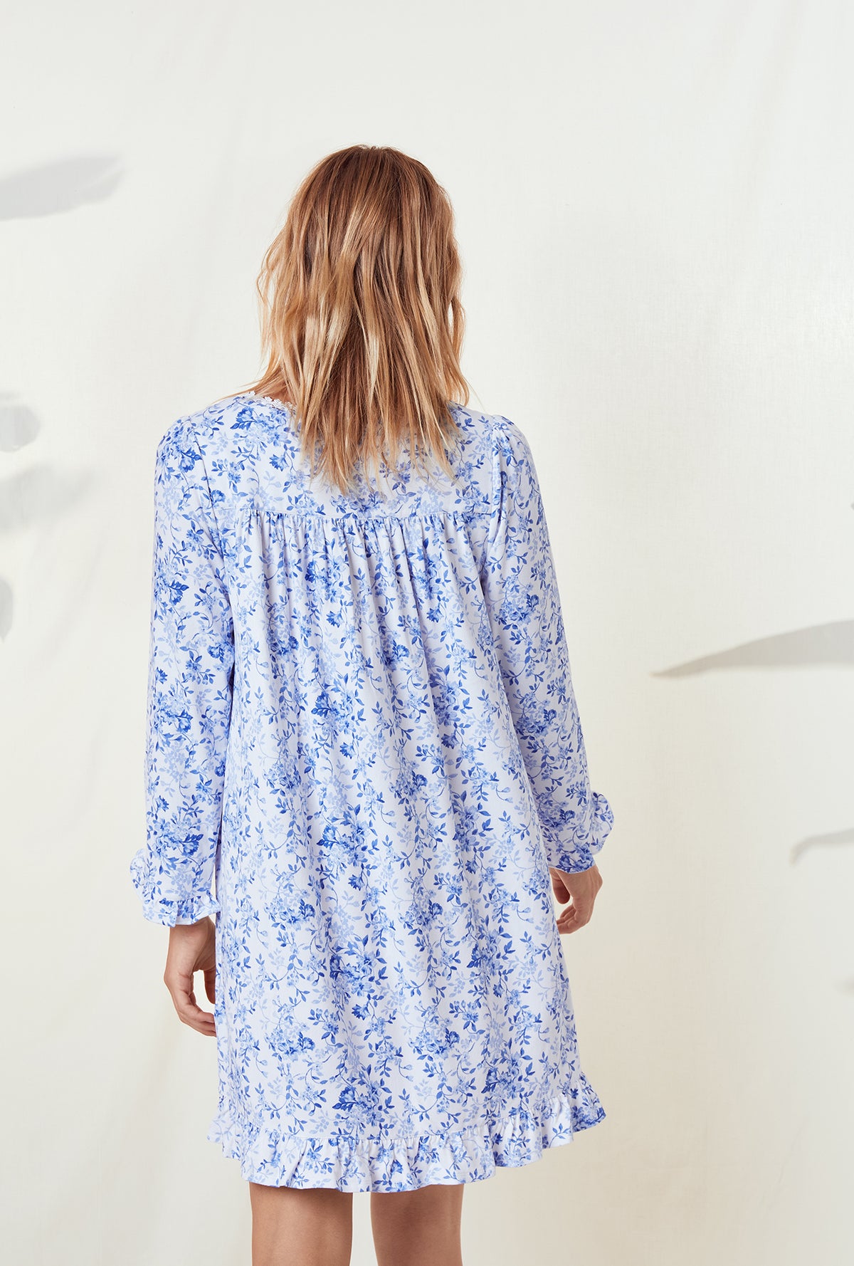 A lady wearing a blue floral long sleeve knit short nightgown.