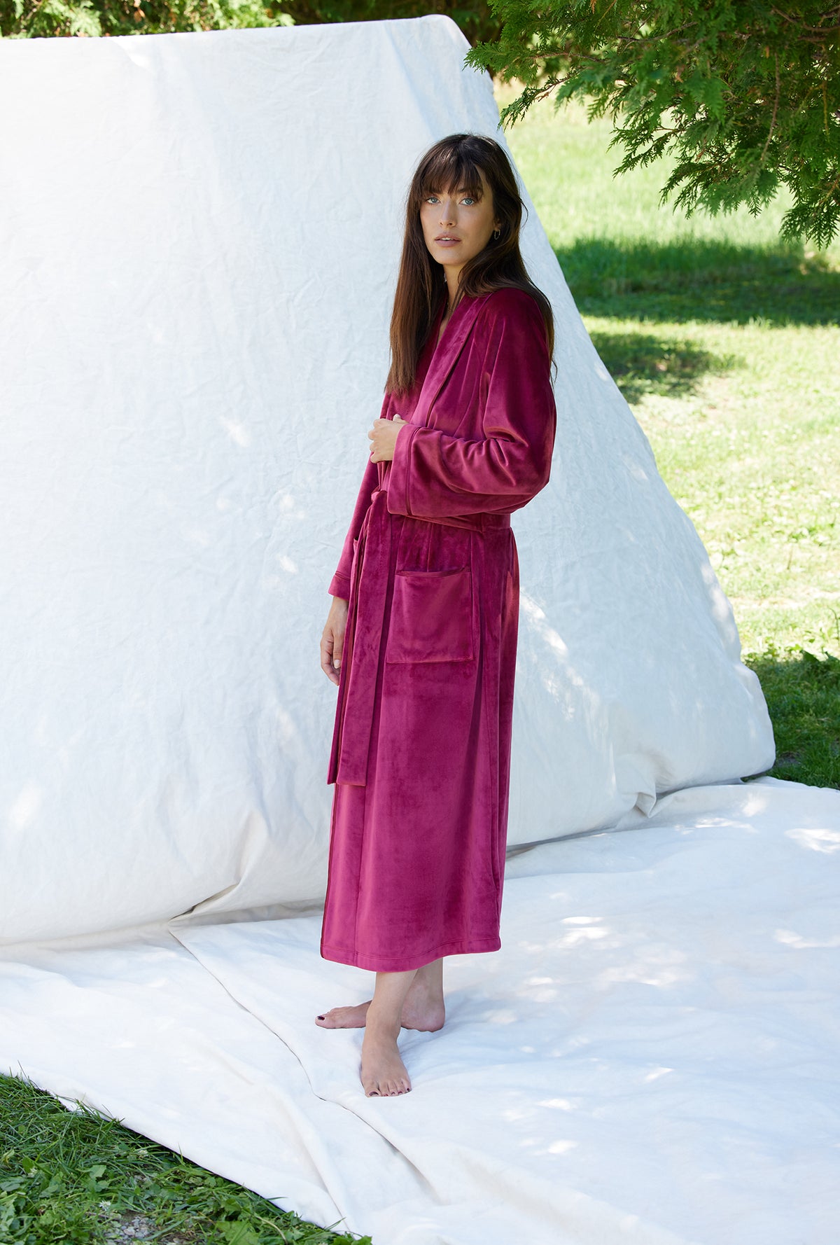 A lady wearing a crimson long sleeve lux velour long wrap robe.