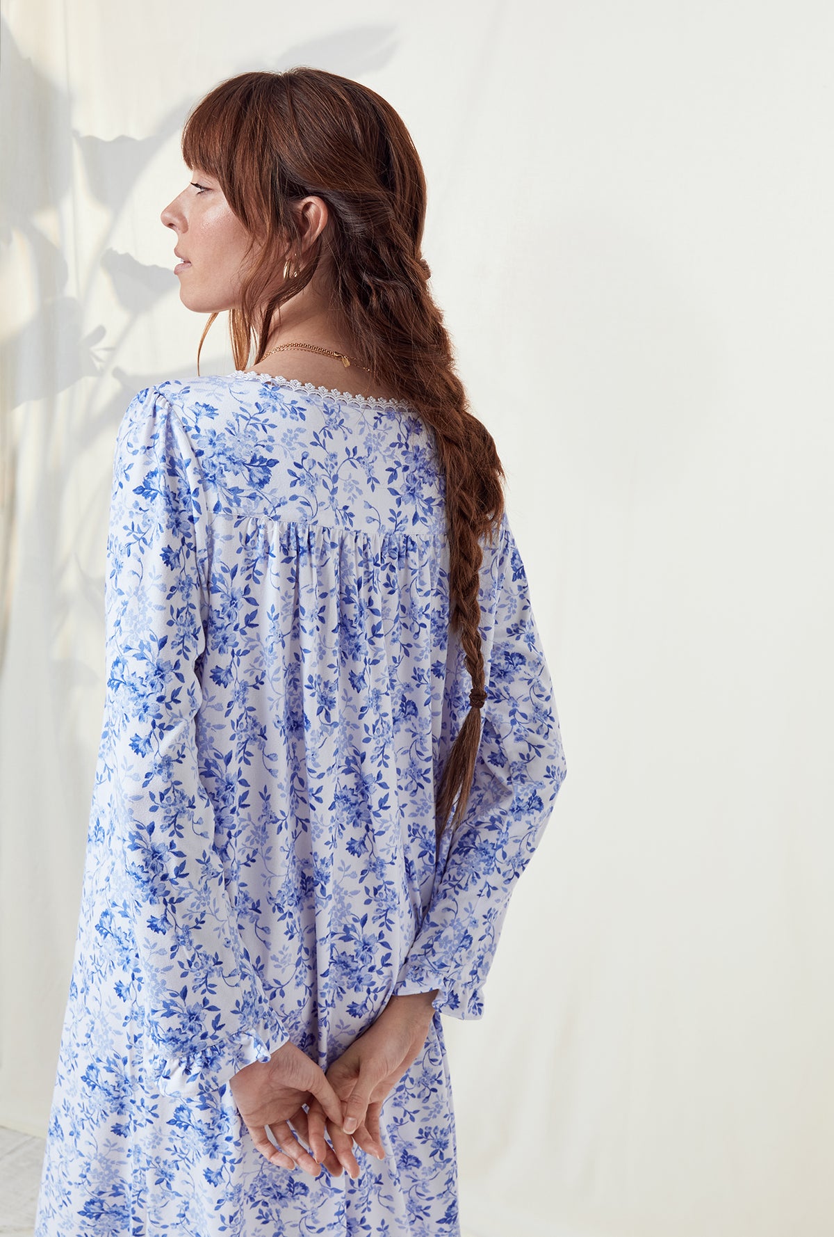 A lady wearing a blue floral long sleeve knit long nightgown..
