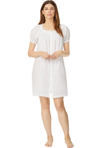 A lady wearing a white cap sleeve short nightdress with white dot pattern.