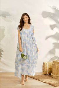 A lady wearing white cap sleeve button front robe nightgown with hydrangea blossom print.