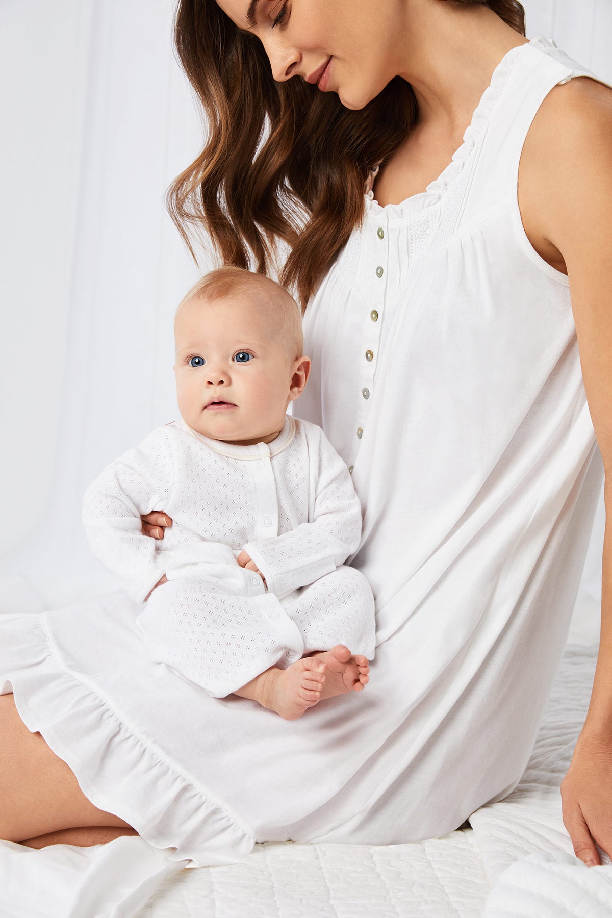 A lady wearing white sleeveless short gown and a baby with a white dress