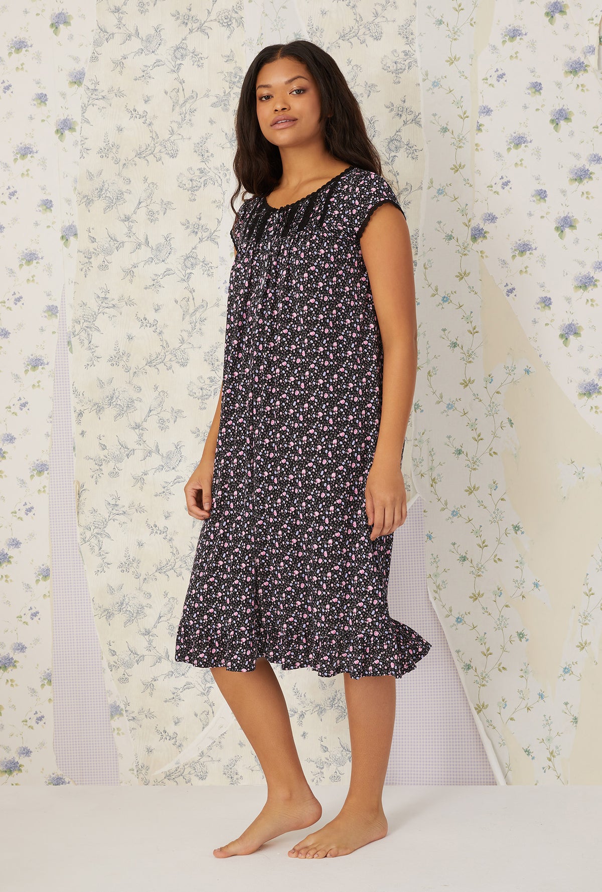 A lady wearing black cap sleeve cotton modal waltz knit nightgown with night blooms print.